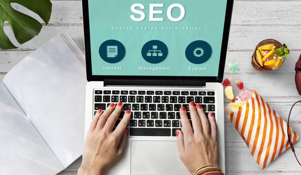 Vue de dessus d'un ordinateur portable affichant une interface SEO avec les piliers Content, Management et System